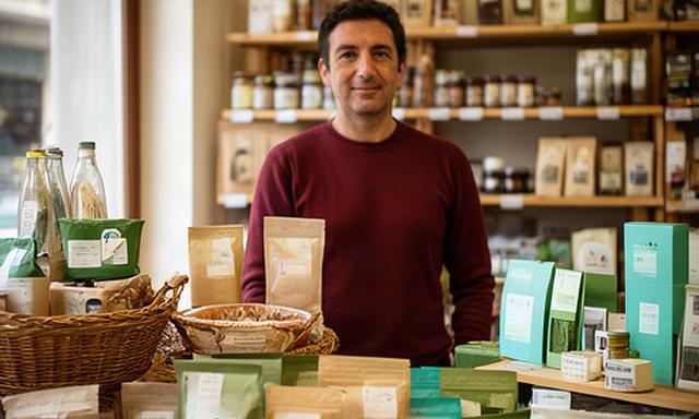 Commerciante dietro il banco di un negozio di quartiere a Prato con prodotti esposti